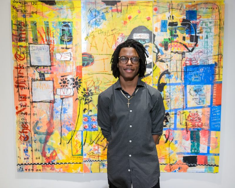 Njari Anderson standing in front of colorful artwork
