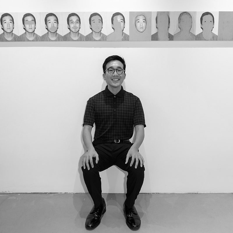 Andrew Kim sitting in front of artwork