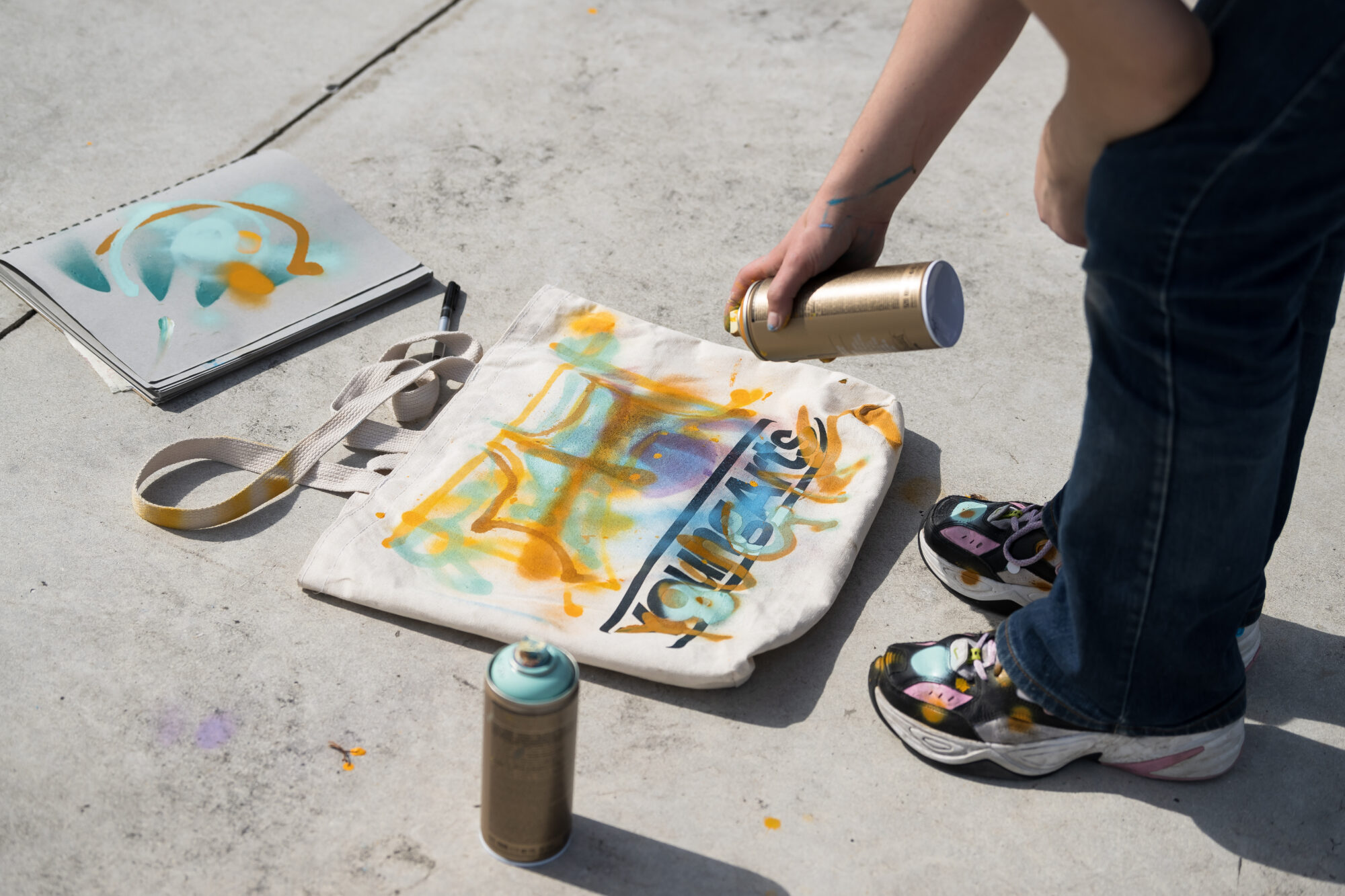 YoungArts tote bag on cement floor with a spray painting the bag