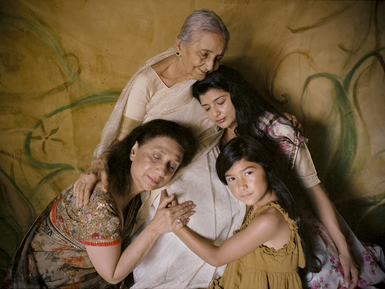 Four women across generations in front of yellow background photographed by Zayira