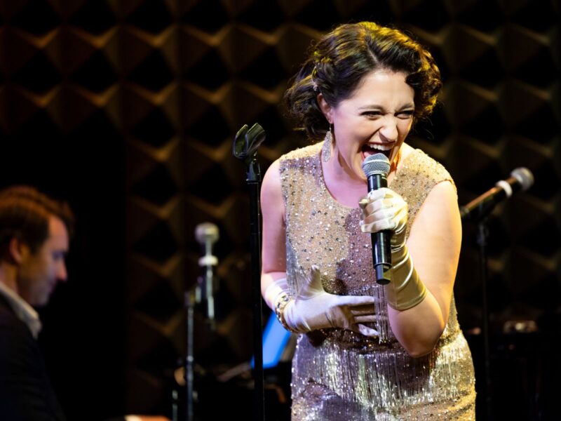Katerina McCrimmon in a sparkling gold dress singing on stage at Joe's Pub